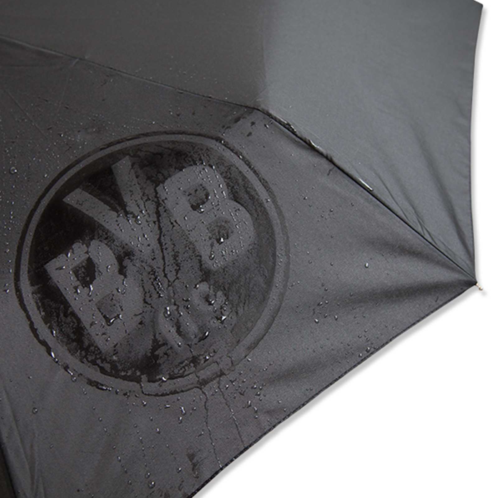Detailansicht des schwarzen BVB-Regenschirms Automatik mit großem, dezentem BVB-Emblem und sichtbaren Wassertropfen auf der Bespannung.