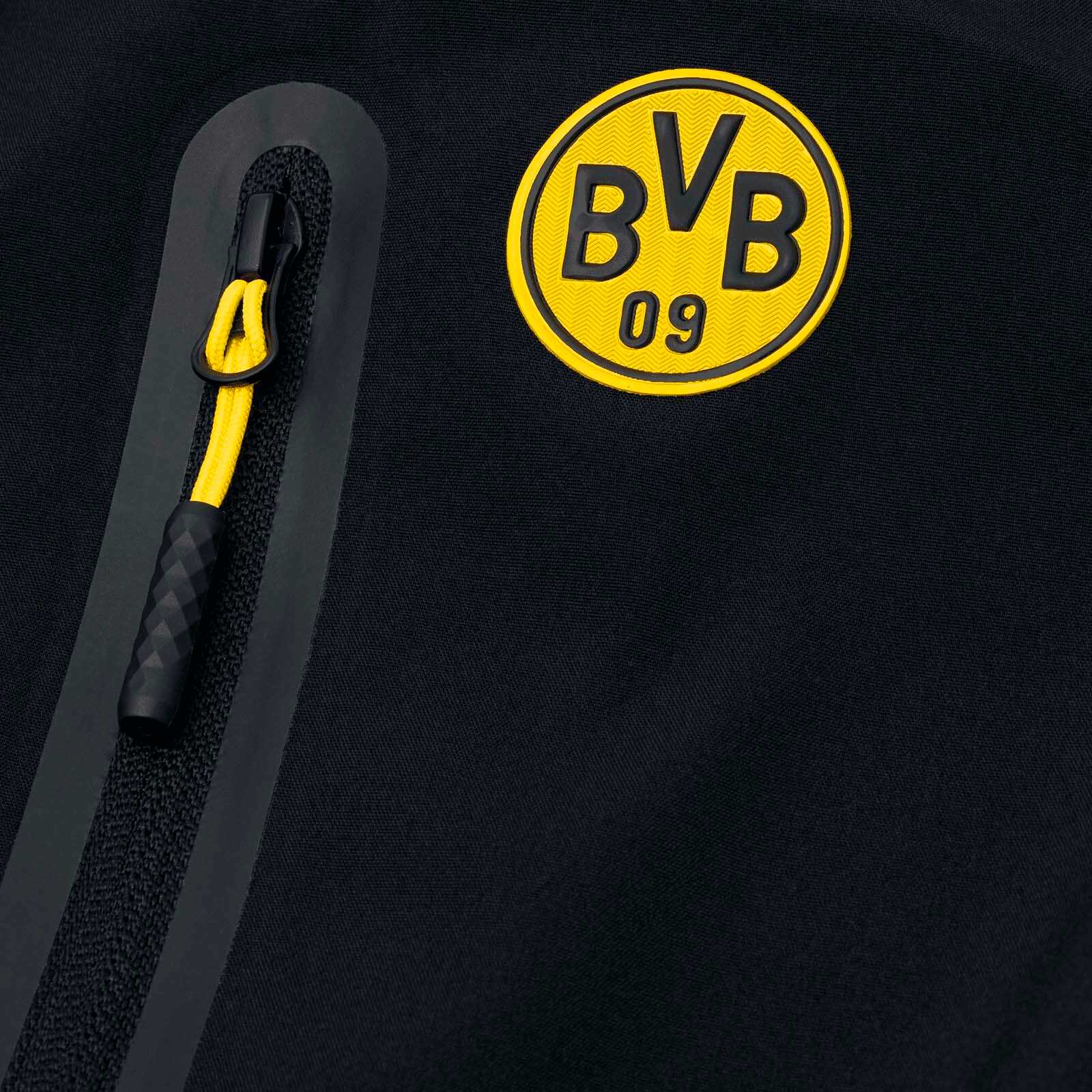 Detailansicht der BVB-Softshelljacke Kinder in schwarzgelb mit BVB-Emblem und Reißverschluss mit gelber Schlaufe.