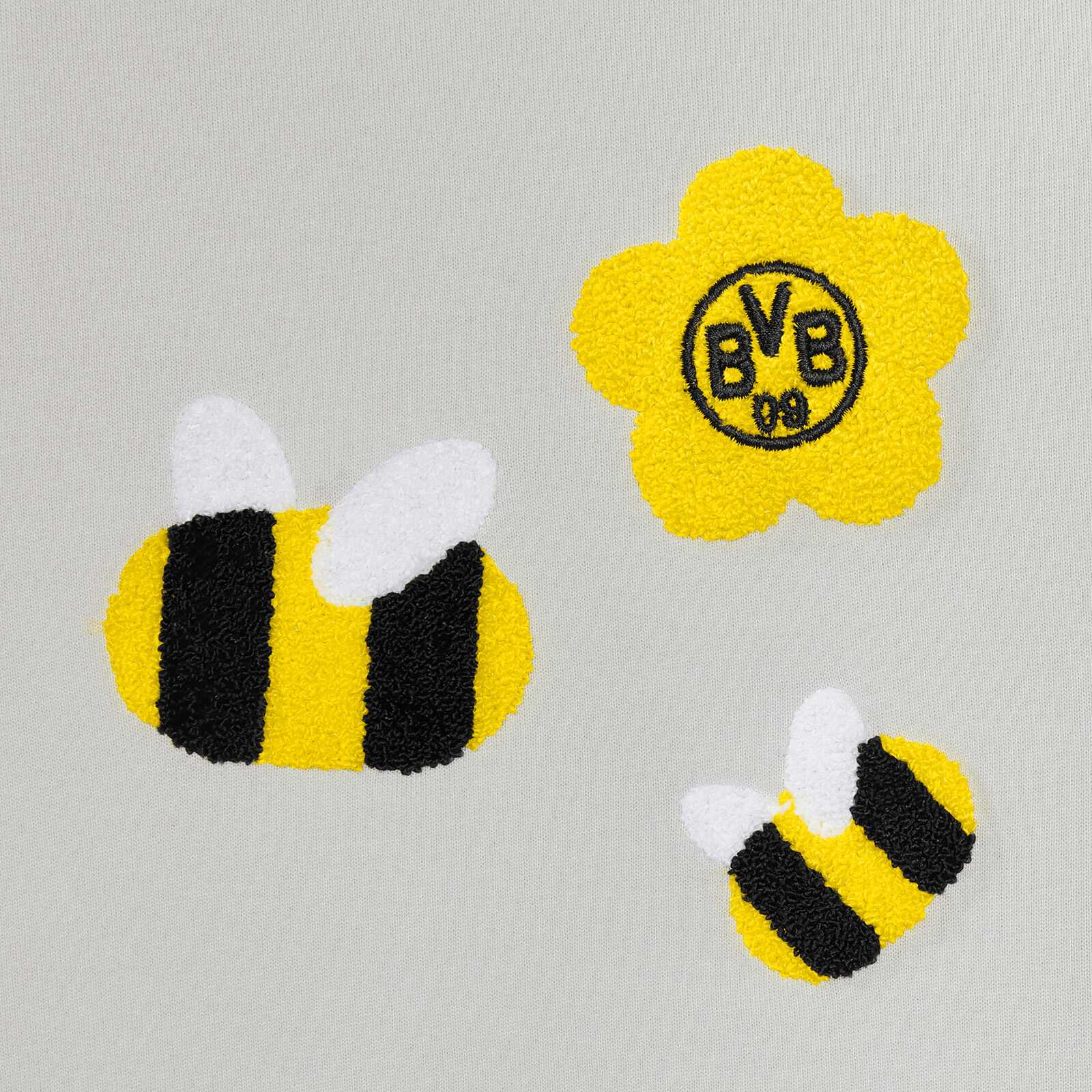 Detailansicht des BVB Bienen Sweater Baby mit zwei gestickten schwarzgelben Bienen und einer gelben Blume mit BVB-Emblem auf hellem Stoff.