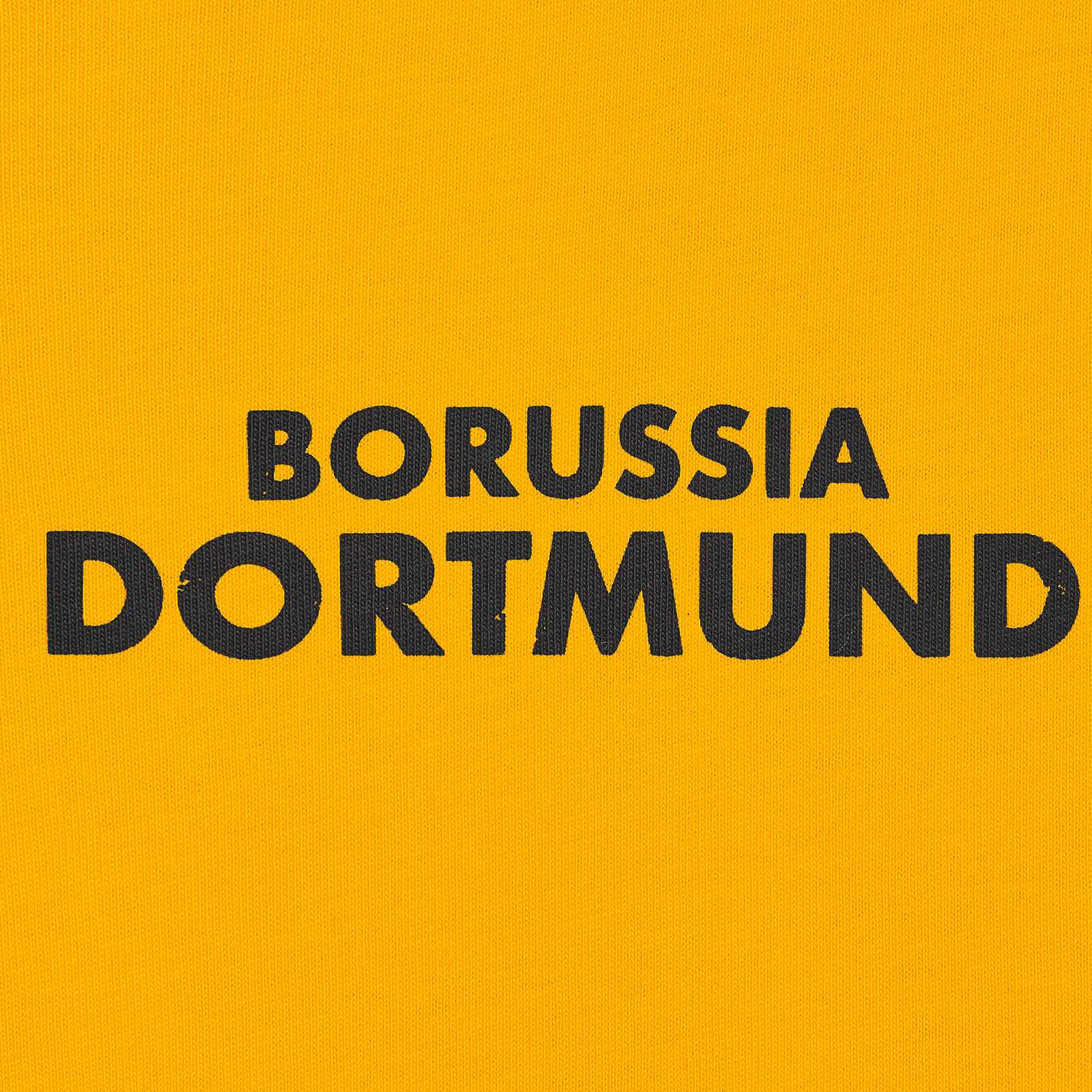 Detailansicht des gelben BVB Retro T-Shirts mit schwarzem „BORUSSIA DORTMUND“-Schriftzug auf der Brust.