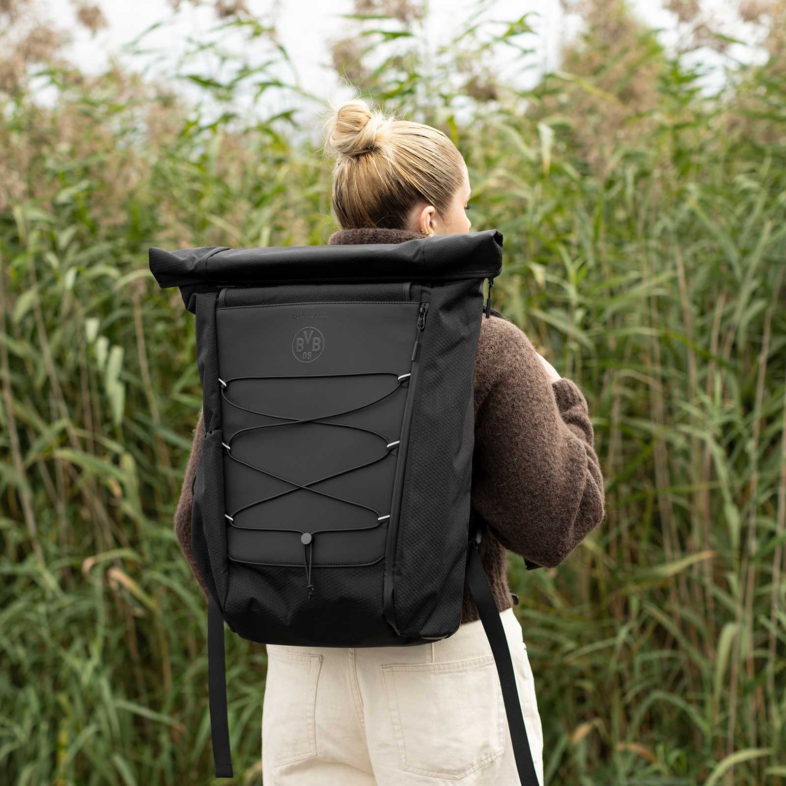 Rückansicht einer Person mit dem BVB X Kapten & Son Banff All Black Rucksack, komplett schwarz mit BVB-Emblem und elastischer Schnürung vorne.