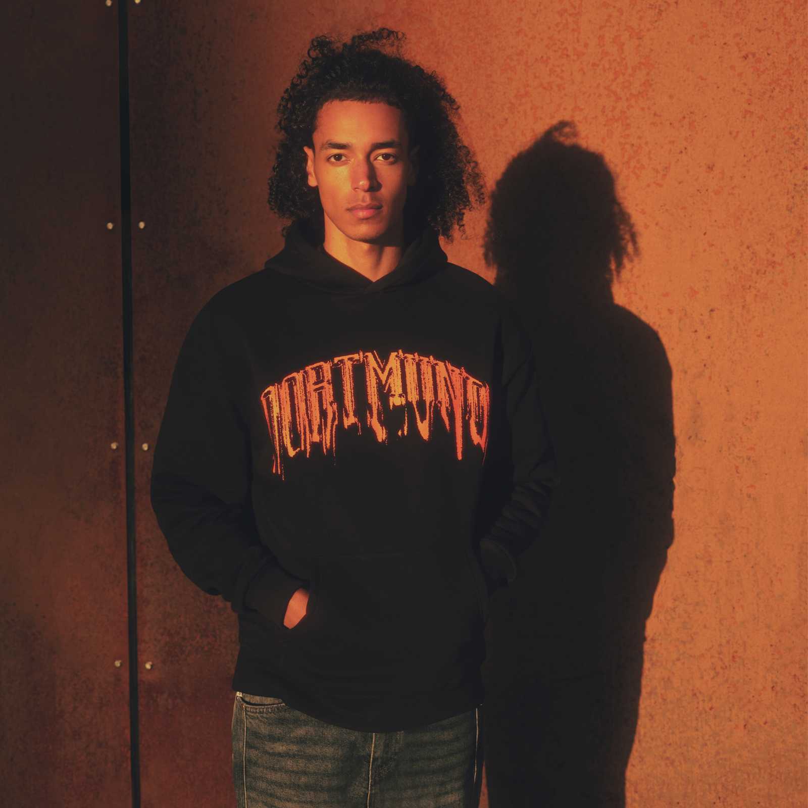 Ein männliches Model trägt den schwarzen Hoodie