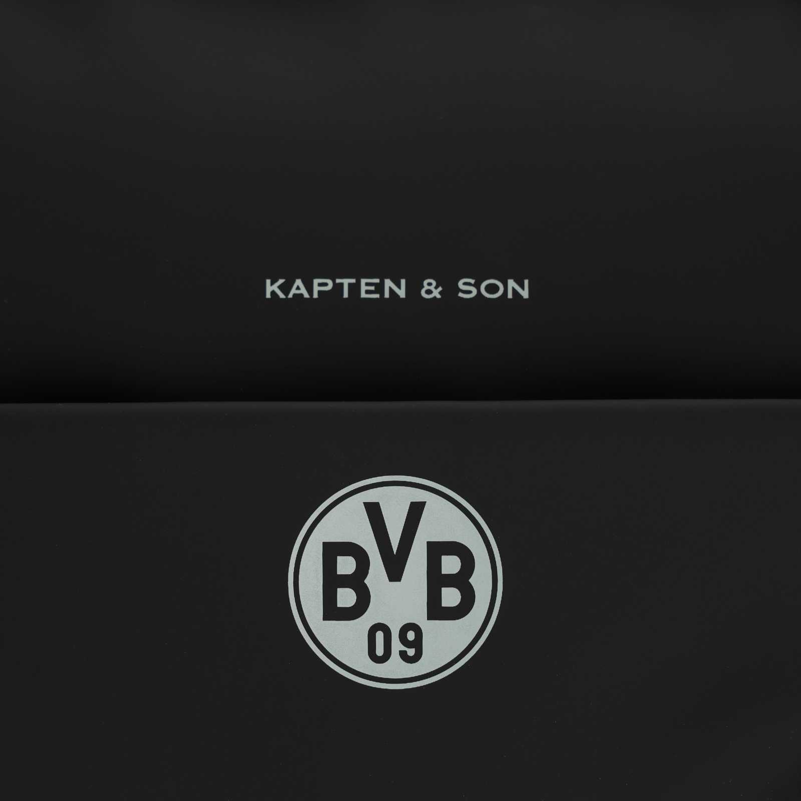 Detailansicht des grauen BVB-Emblems und des Kapten & Son Schriftzugs