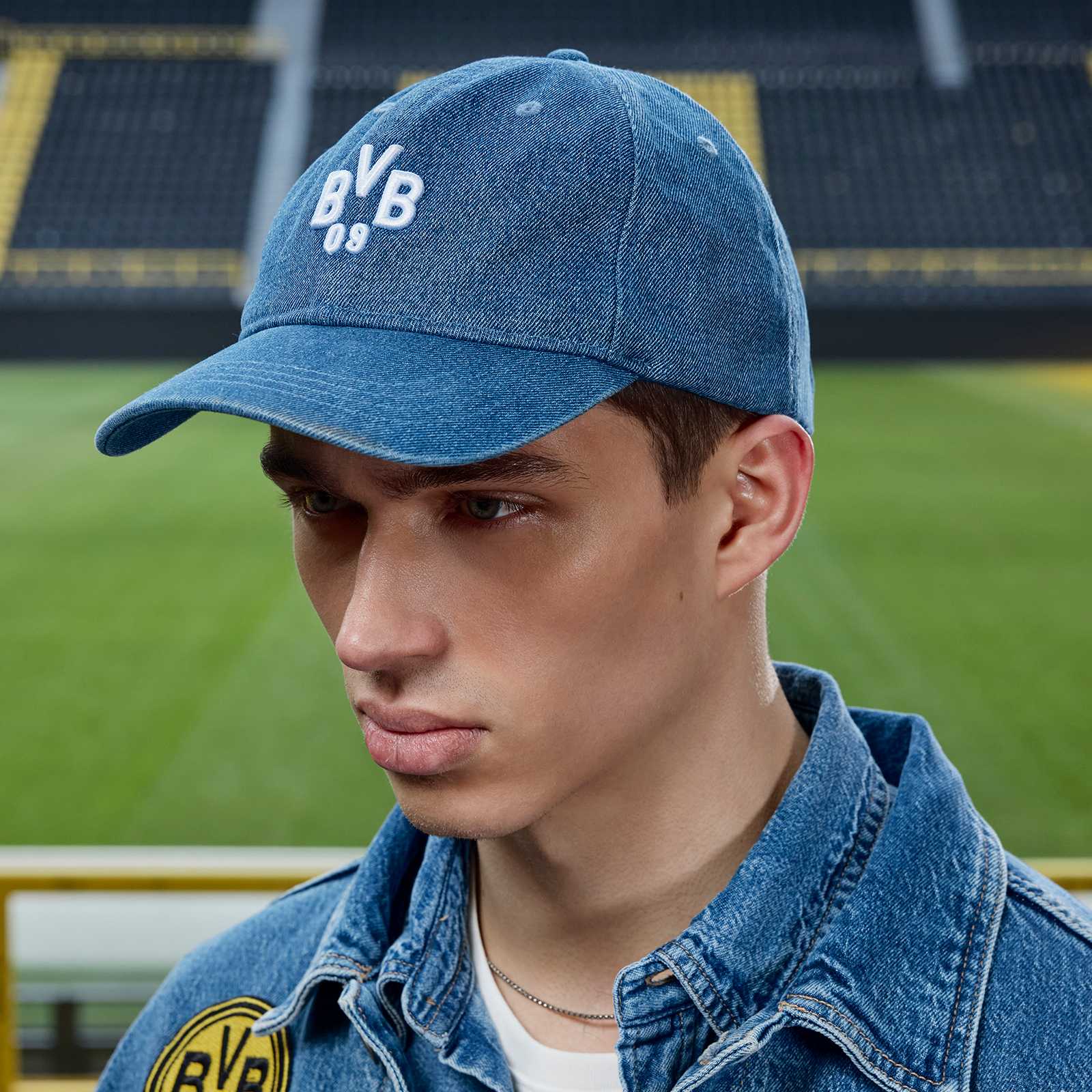 Ein männliches Model im Stadion trägt die Kappe und schaut zur Seite