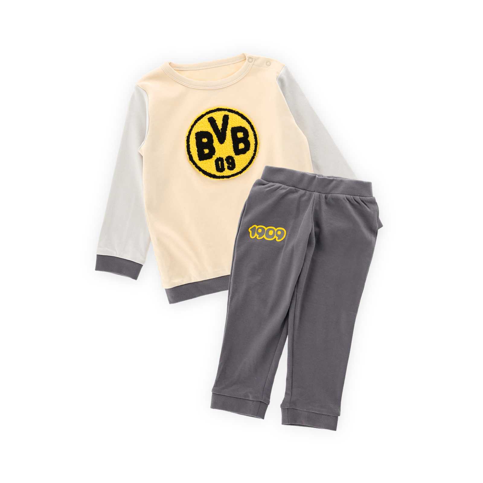 Die Vorderansicht des Joggingsets bestehend aus einem beigen Sweatshirt mit großem BVB-Logo auf dem Bauch und einer grauen Hose mit BVB09-Schriftzug auf dem Bein